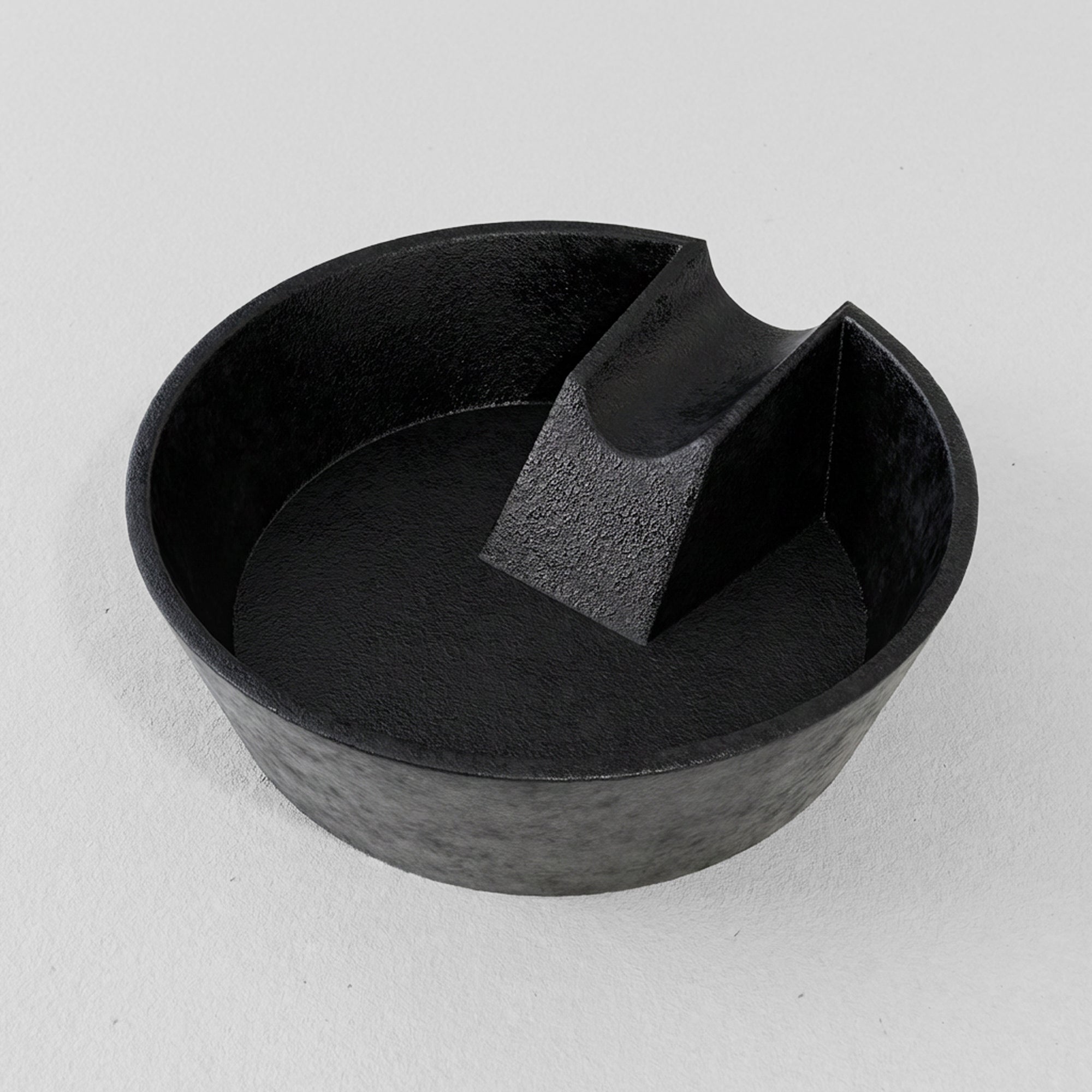 Black cast iron ashtray with a unique design on a light gray background